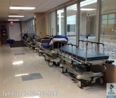 beds in hall before overhead medical gurney lifts or vertically stacked bed racks