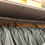 baseball equipment room with organized uniform racks and bat storage shelves