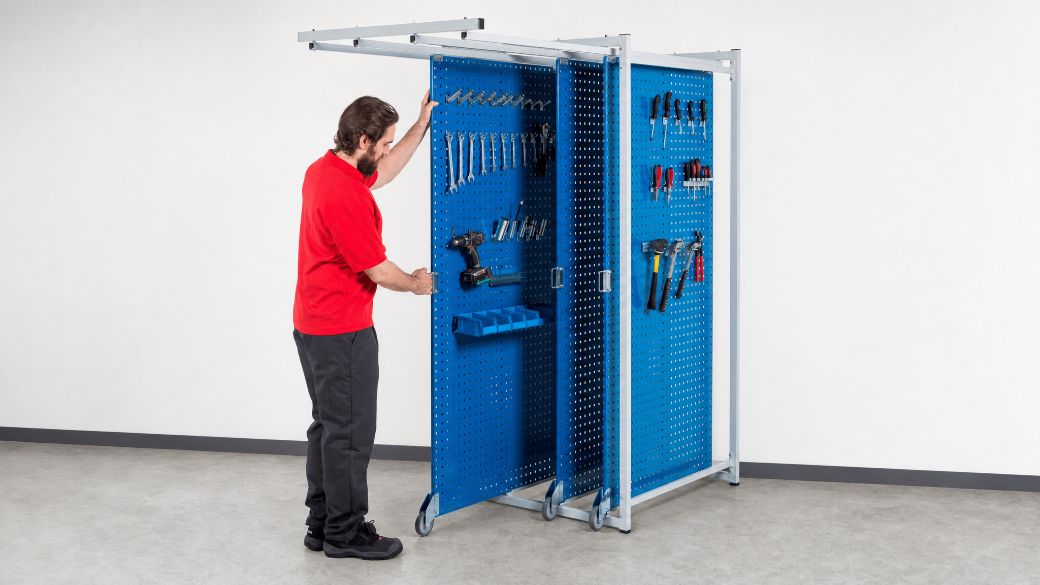Person sliding a blue pegboard storage rack filled with various hand tools.